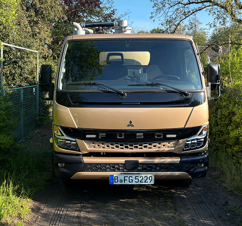 Frontansicht kleiner Saugwagen auf schmalem Weg Gartensparte