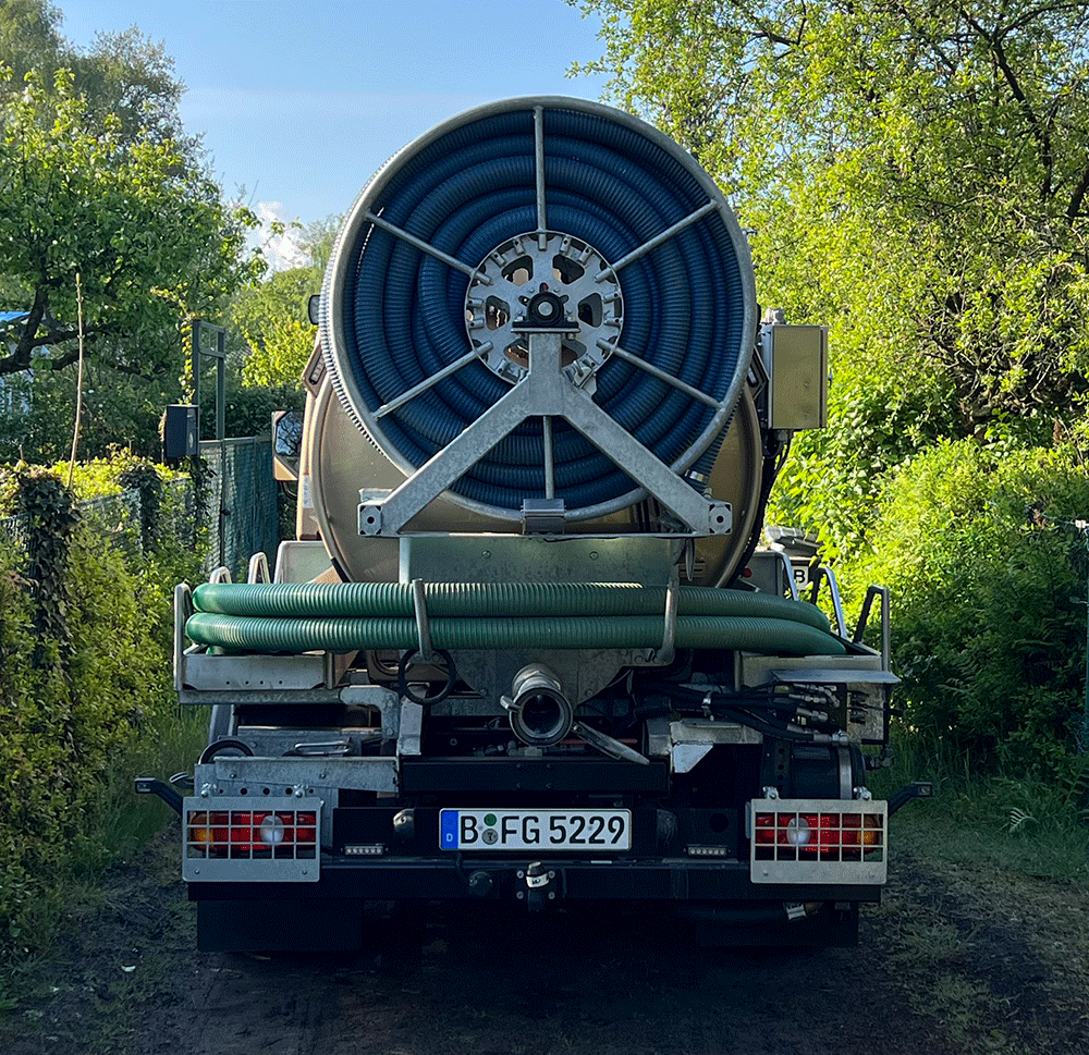 Rückansicht kleiner Saugwagen auf schmalem Weg Gartensparte