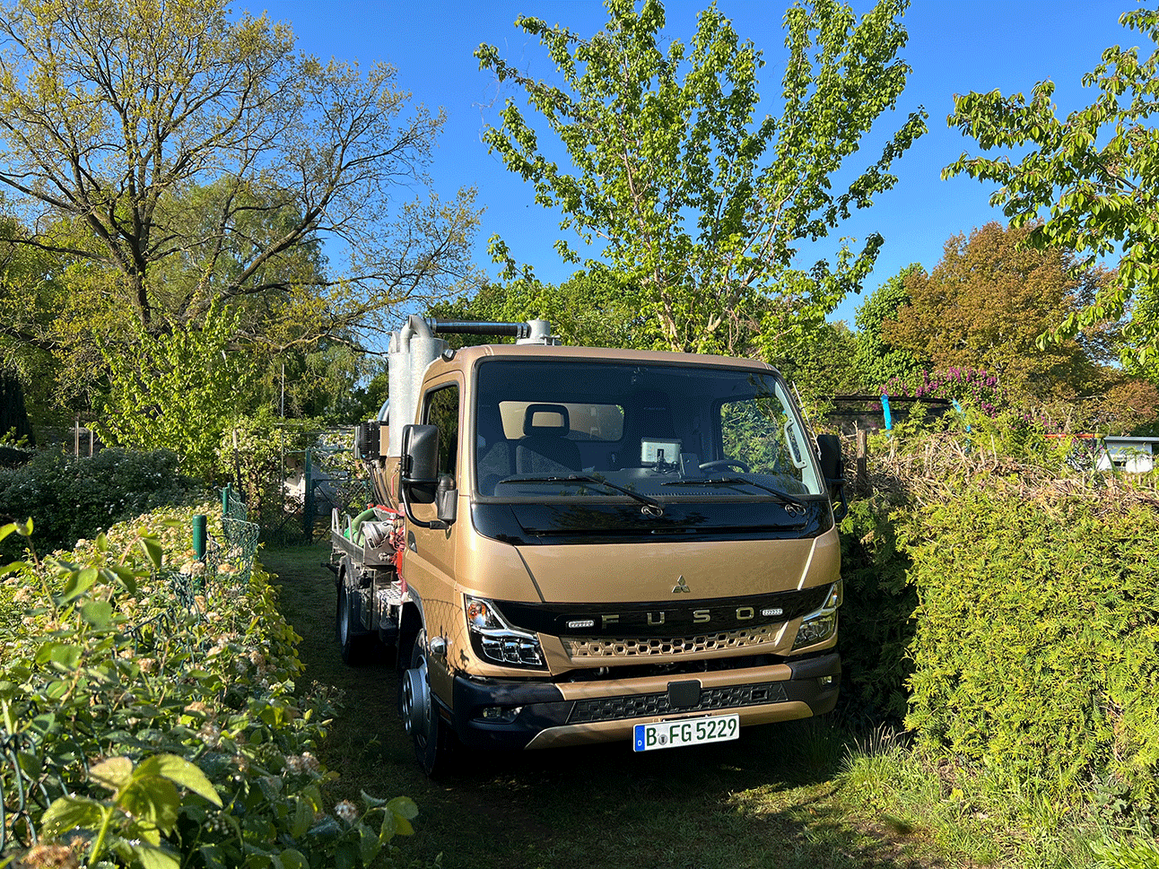 Ansicht kleiner Saugwagen auf schmalem Weg Gartensparte
